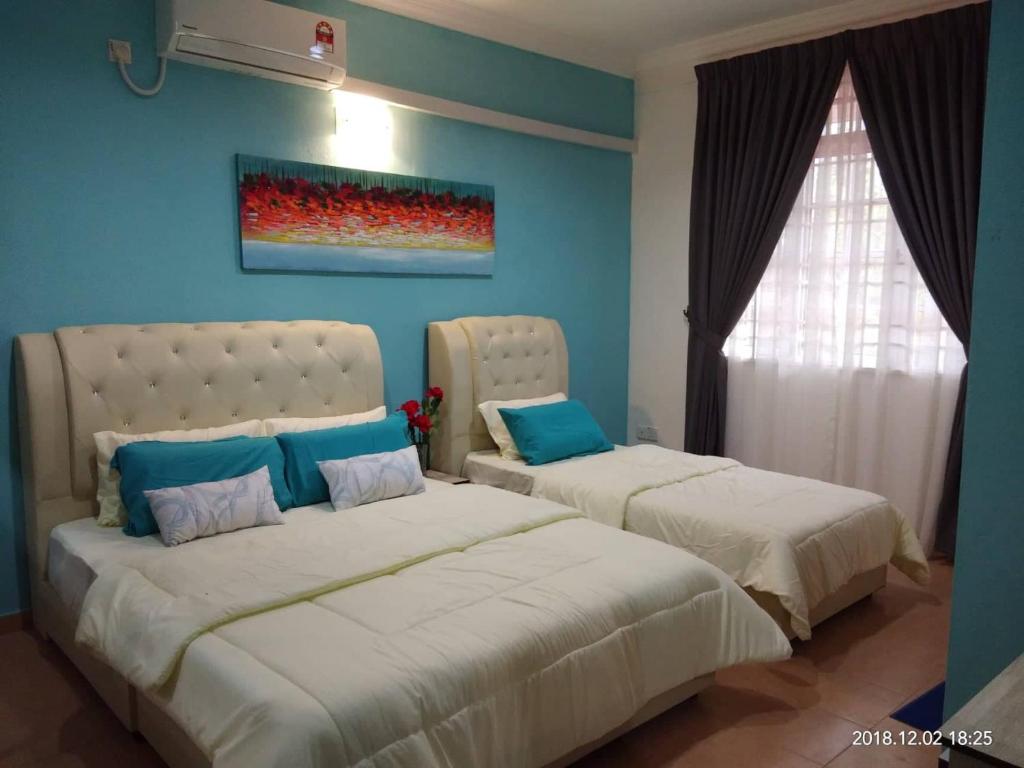 2 camas en un dormitorio con paredes azules en aAdy Homestay, en Ketereh