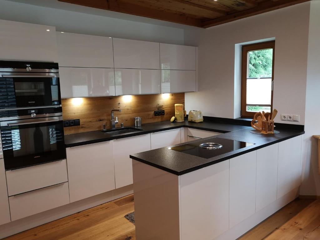 a kitchen with white cabinets and a black counter top at Appartement Klinger in Eben im Pongau