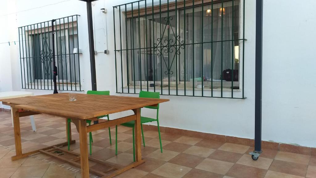 a wooden table with green chairs next to a building at C&B LOLA - Habitacion privada - Aire acondicionado - Baños compartidos in Puerto Real