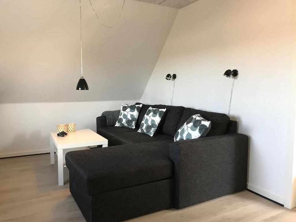 a living room with a black couch and a table at Vesterhavsvej in Hvide Sande