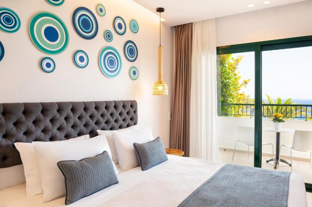 a bedroom with a large bed and a wall with plates at Kalidon Panorama Hotel in Kokkari