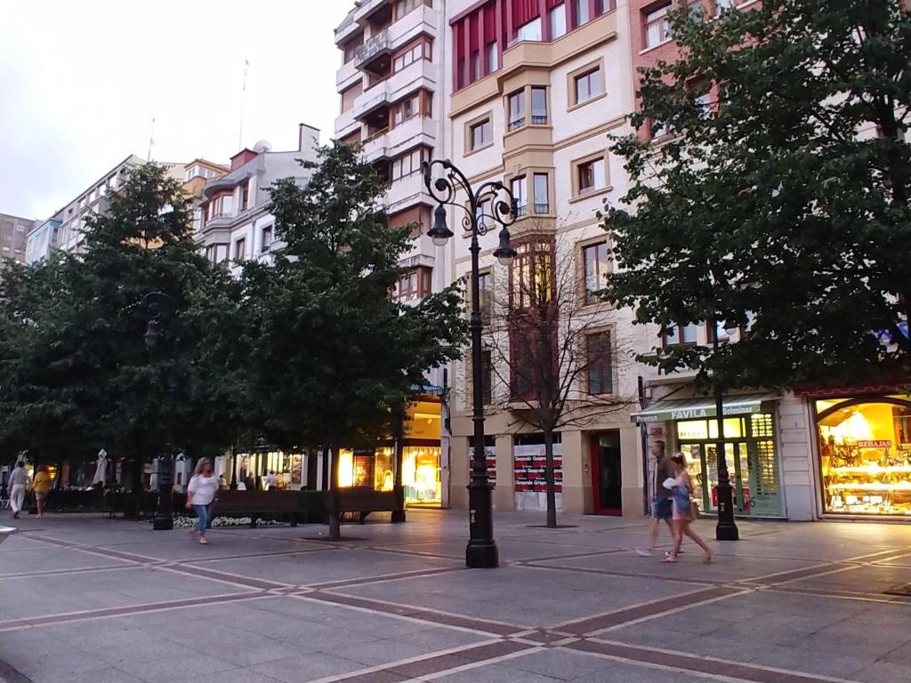 una calle con gente caminando en una calle de la ciudad con edificios en Hogar, a modo de hotel, en Gijón