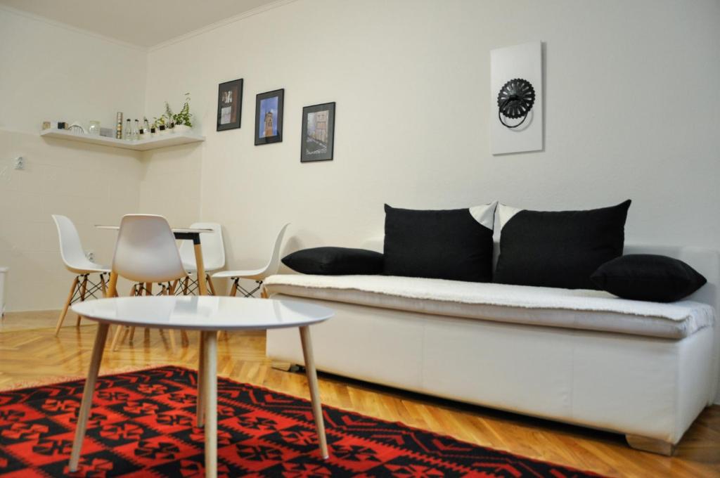 Zvekir - Old Town Apartment في سراييفو: غرفة معيشة مع أريكة بيضاء وطاولة