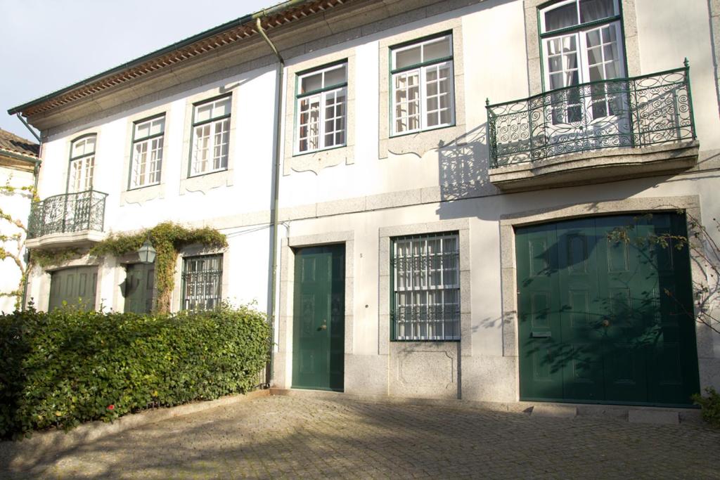 un edificio blanco con puertas y ventanas verdes en Casa Do Castelo, en Guimarães