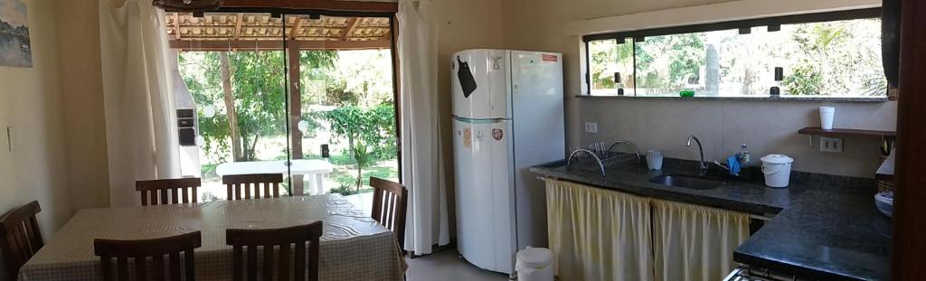 cocina con nevera blanca y mesa con sillas en Nova Casa Laranjeiras, en Garopaba