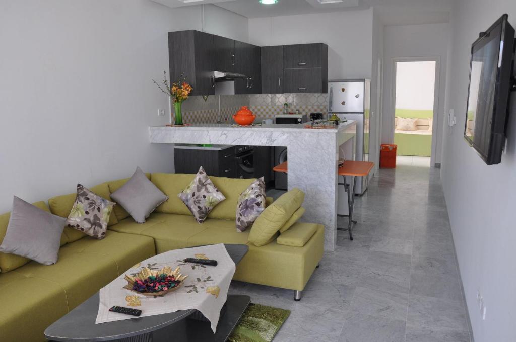 un soggiorno con divano giallo e una cucina di Apartment zone touristique 80 m beach free wifi a Mahdia