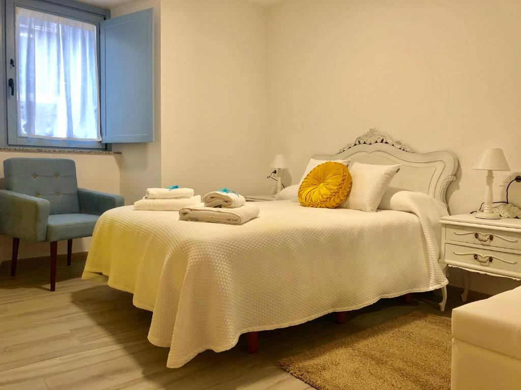 ein Schlafzimmer mit einem weißen Bett und einem blauen Stuhl in der Unterkunft Apartamentos Turísticos Casa Dina in Rinlo