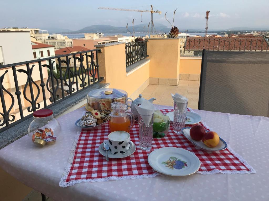 アルゲーロにあるB&B Su Canistredduの赤白のテーブルクロスに食べ物と飲み物をかけたテーブル