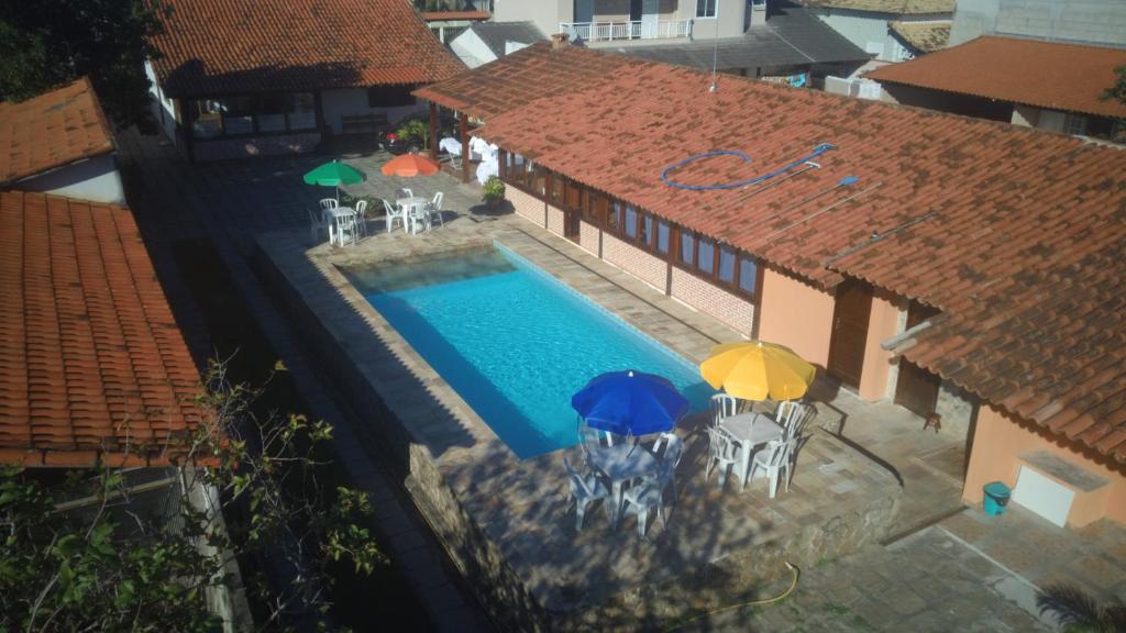 - une vue sur la piscine avec un parasol dans l'établissement Pousada Solar Tropical, à Saquarema