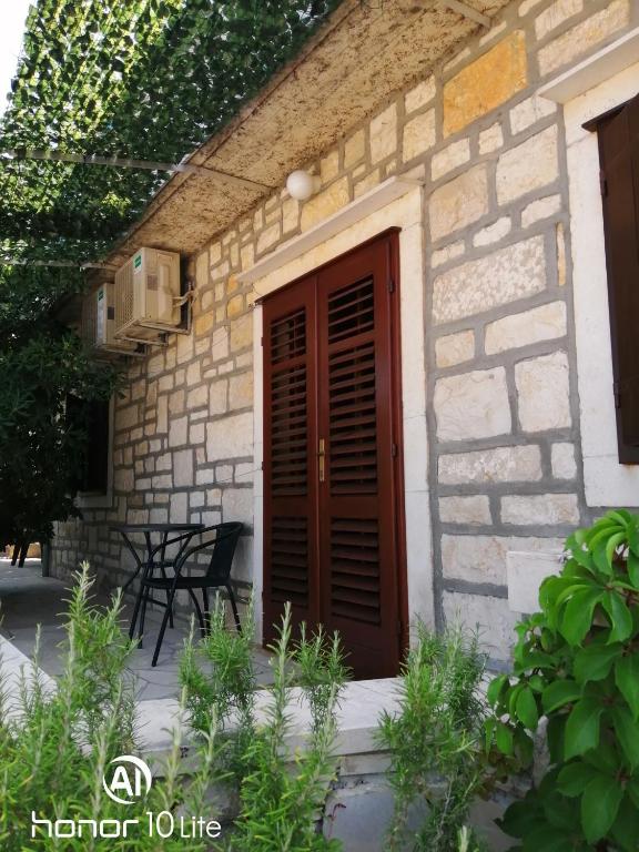 a stone house with a wooden door and chairs at Apartment Karmen in Sumartin
