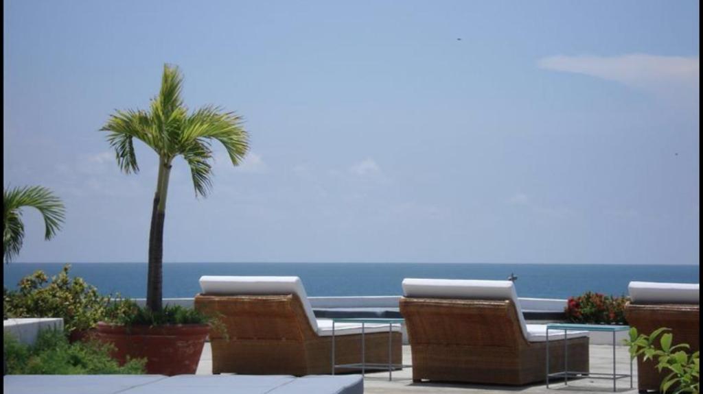 a table and chairs with a palm tree and the ocean at Penthouse Caribbean View and private pool, Cartagena in Cartagena de Indias