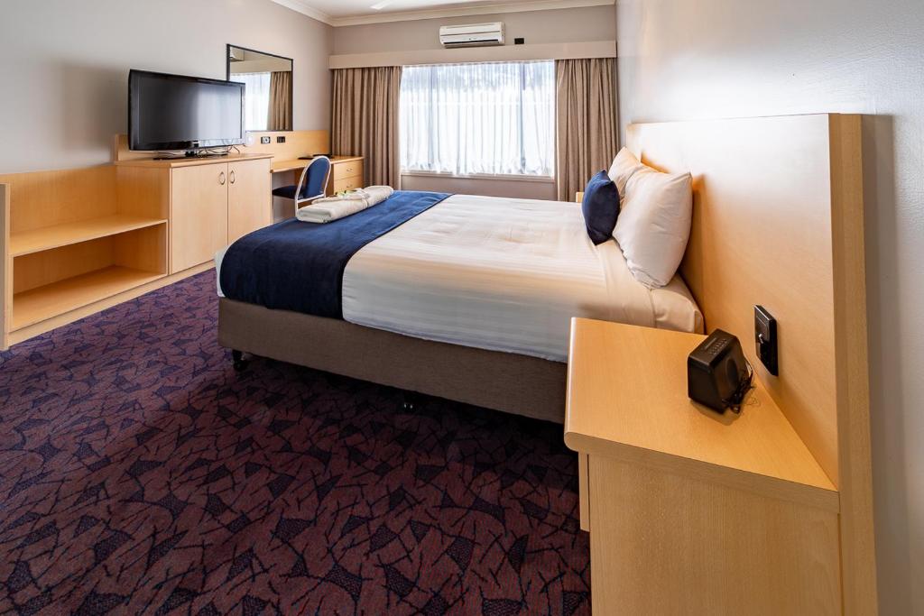 a hotel room with a bed and a flat screen tv at Albert Motel in Moree