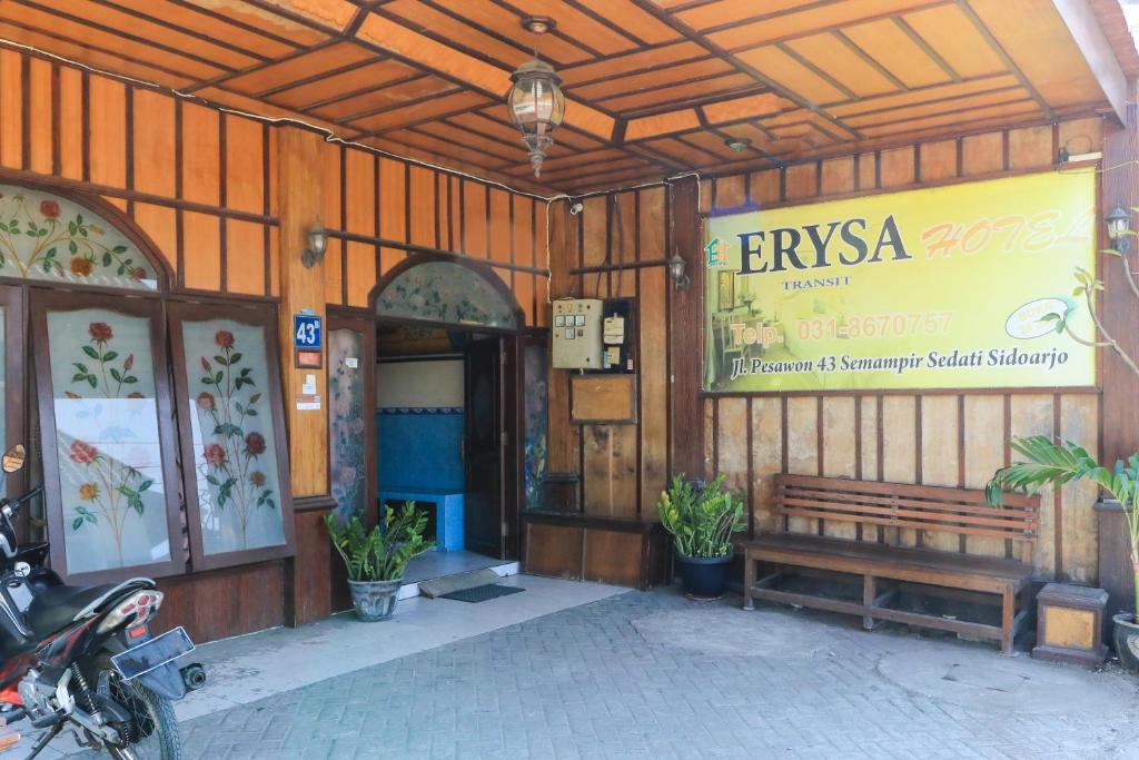 Hotel Erysa Juanda في Sedati: مبنى عليه مقعد وعلامة عليه