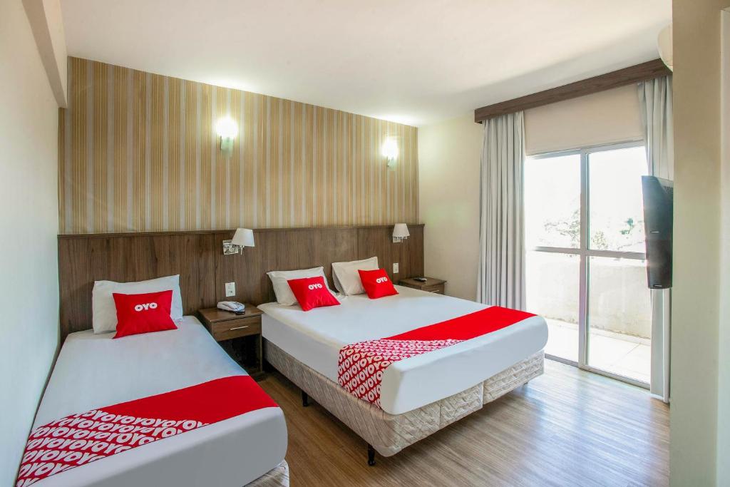 two beds in a hotel room with red pillows at OYO Urupema Hotel, São Paulo in São José dos Campos