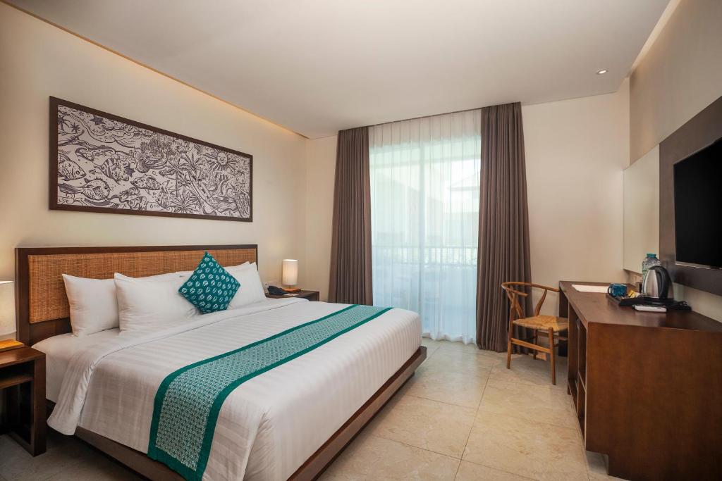 a bedroom with a bed and a desk and a television at Anja Jimbaran in Jimbaran