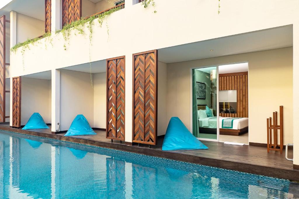 a swimming pool with blue pillows next to a house at Anja Jimbaran in Jimbaran