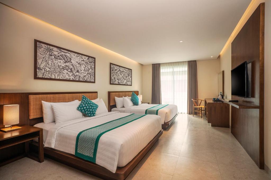 a hotel room with two beds and a television at Anja Jimbaran in Jimbaran