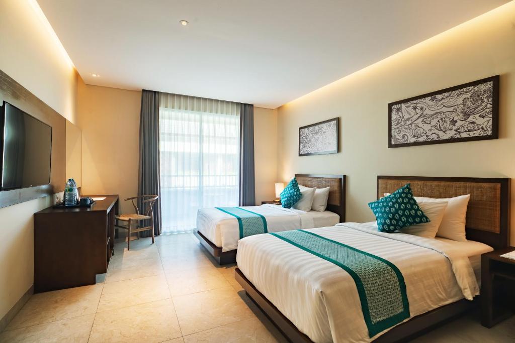 a hotel room with two beds and a flat screen tv at Anja Jimbaran in Jimbaran