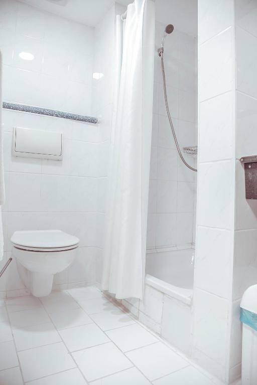 a white bathroom with a shower and a toilet at Shodlik Palace in Tashkent