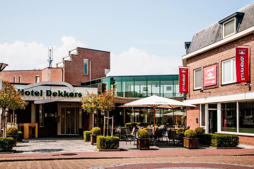 a group of buildings with tables and umbrellas on a street at Hotel Dekkers in Ossendrecht