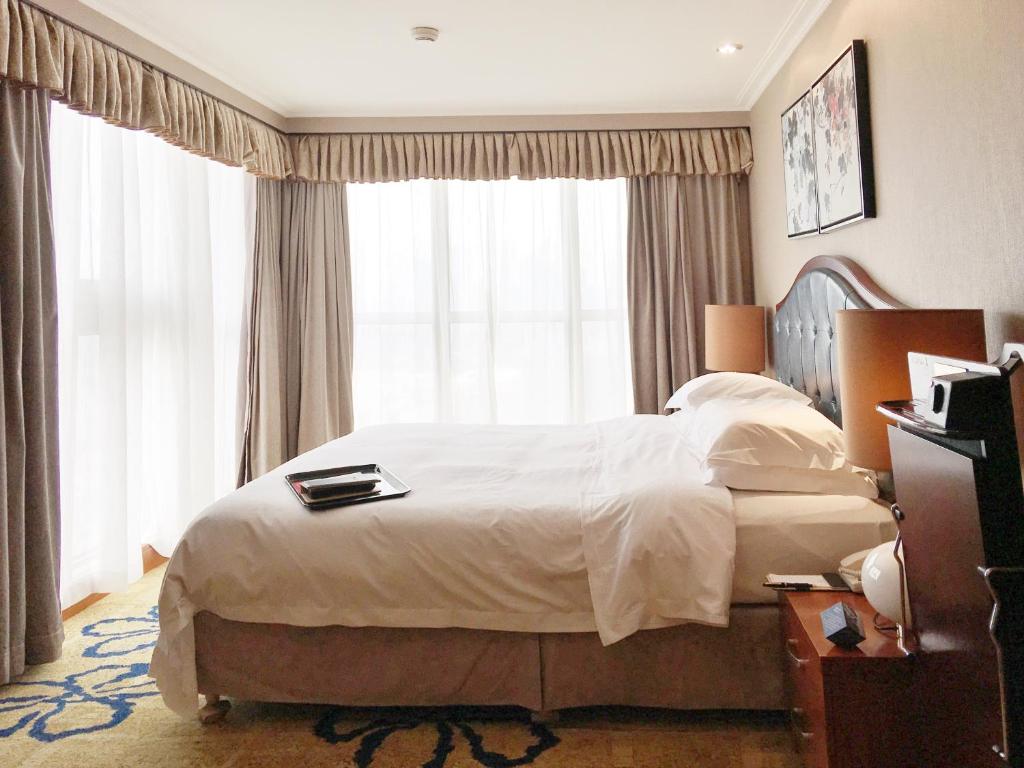um quarto com uma cama grande e uma janela grande em Ramada Plaza Tianlu Hotel em Wuhan
