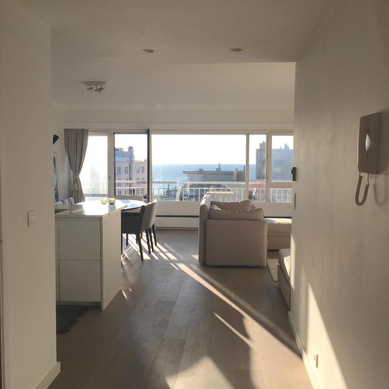 a kitchen and living room with a view of the ocean at sea and city view with double terrace Flat C Oostende in Ostend
