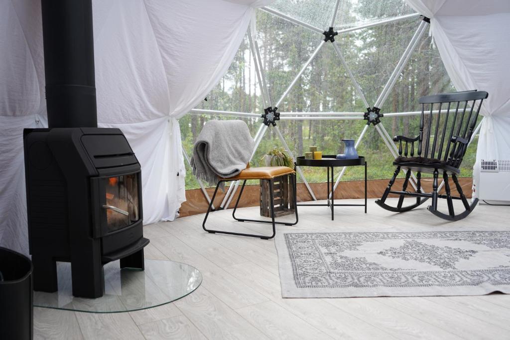 a living room with a fireplace and chairs in a tent at GLØD Aurora Canvas Dome in Alta