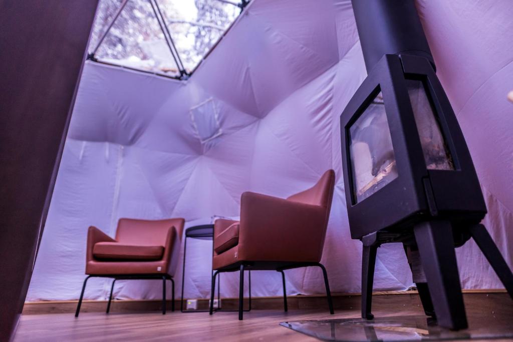 a room with three chairs and a tv in a tent at GLØD Aurora Canvas Dome in Alta
