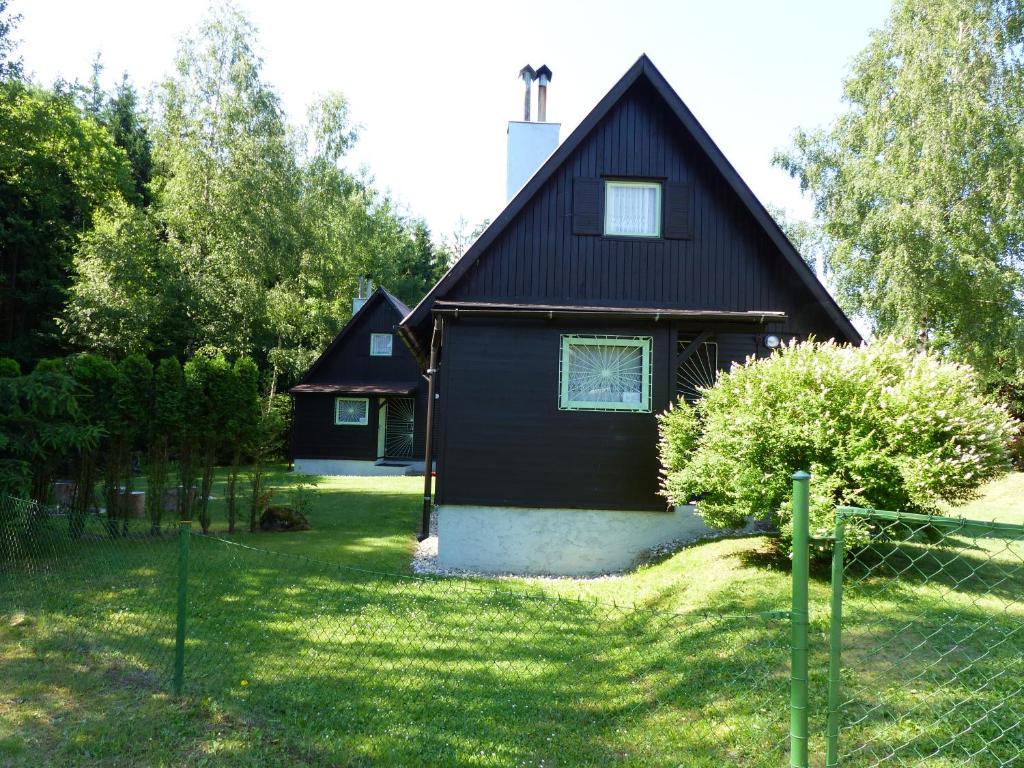 uma casa negra com uma vedação à frente. em Chaty Vysočina em Polesí