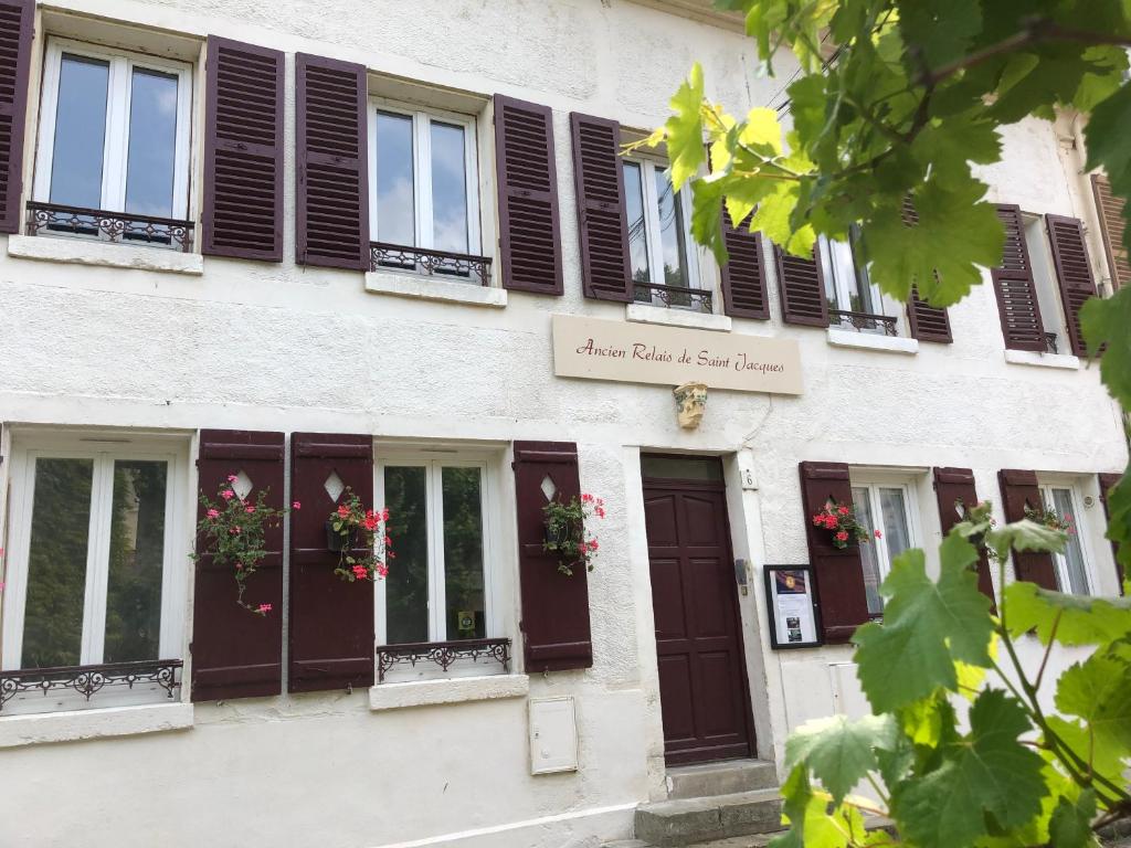 un edificio con persianas negras y flores en las ventanas en Gite Ancien Relais de Saint-Jacques, en La Roche-Guyon