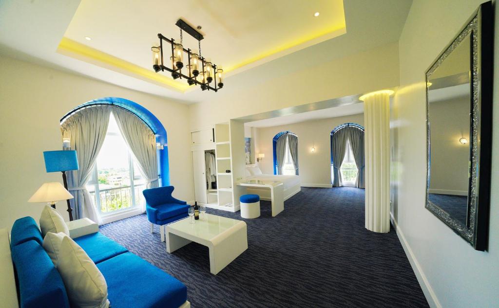 a living room with a blue couch and a bedroom at Hotel Carlito Tagaytay in Tagaytay