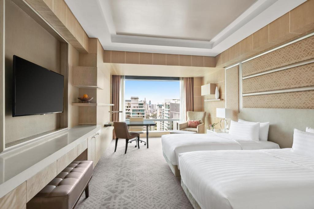 une chambre d'hôtel avec deux lits et une télévision dans l'établissement Shangri-La The Fort, Manila, à Manille