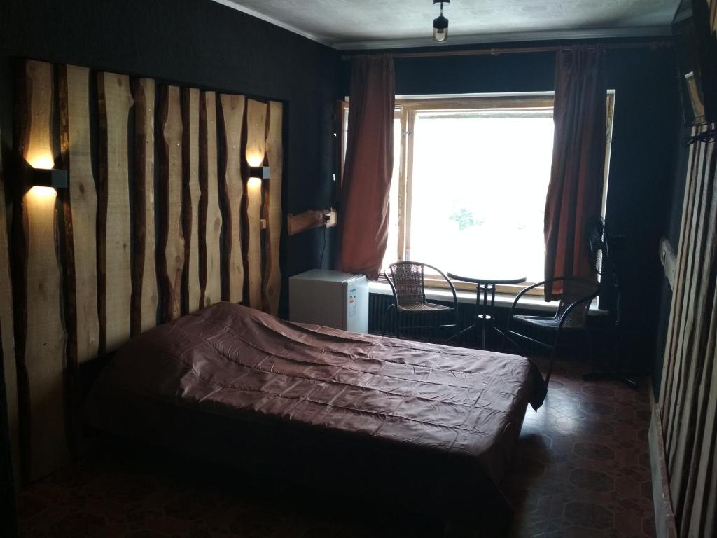 Готель на Автовокзалі في بولتافا: غرفة نوم مع سرير مع اللوح الأمامي الخشبي ونافذة