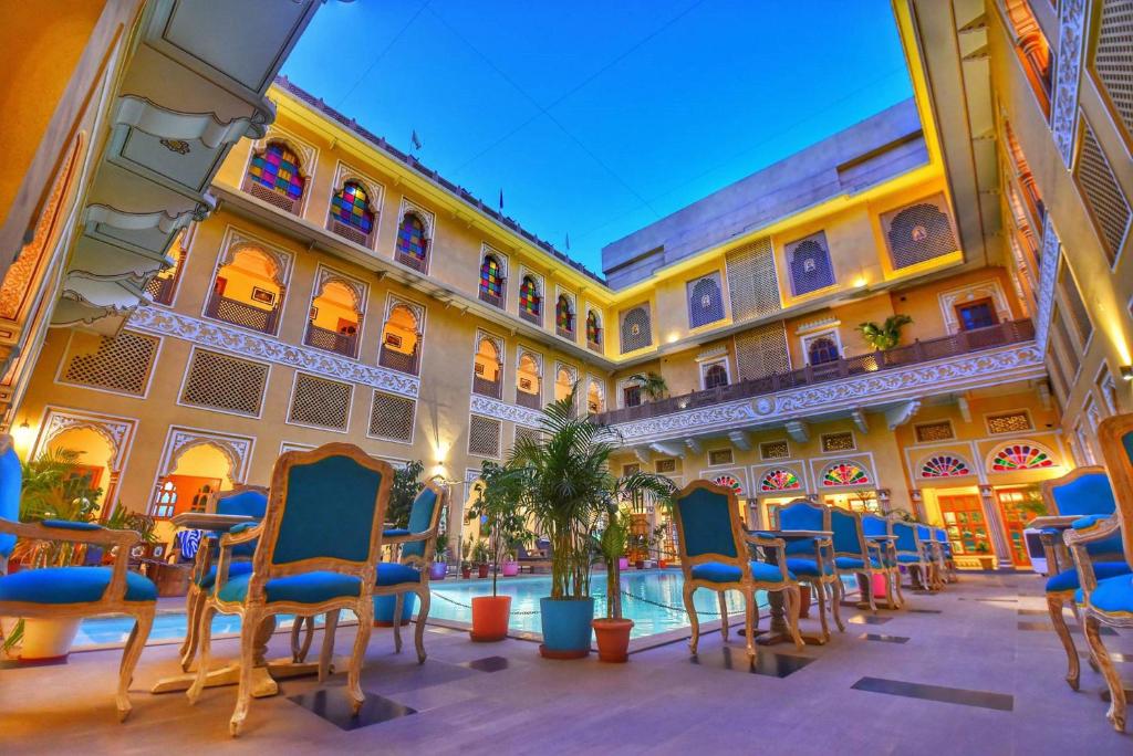 a courtyard with chairs and a pool in a building at Nirbana Palace - A Heritage Hotel and Spa in Jaipur