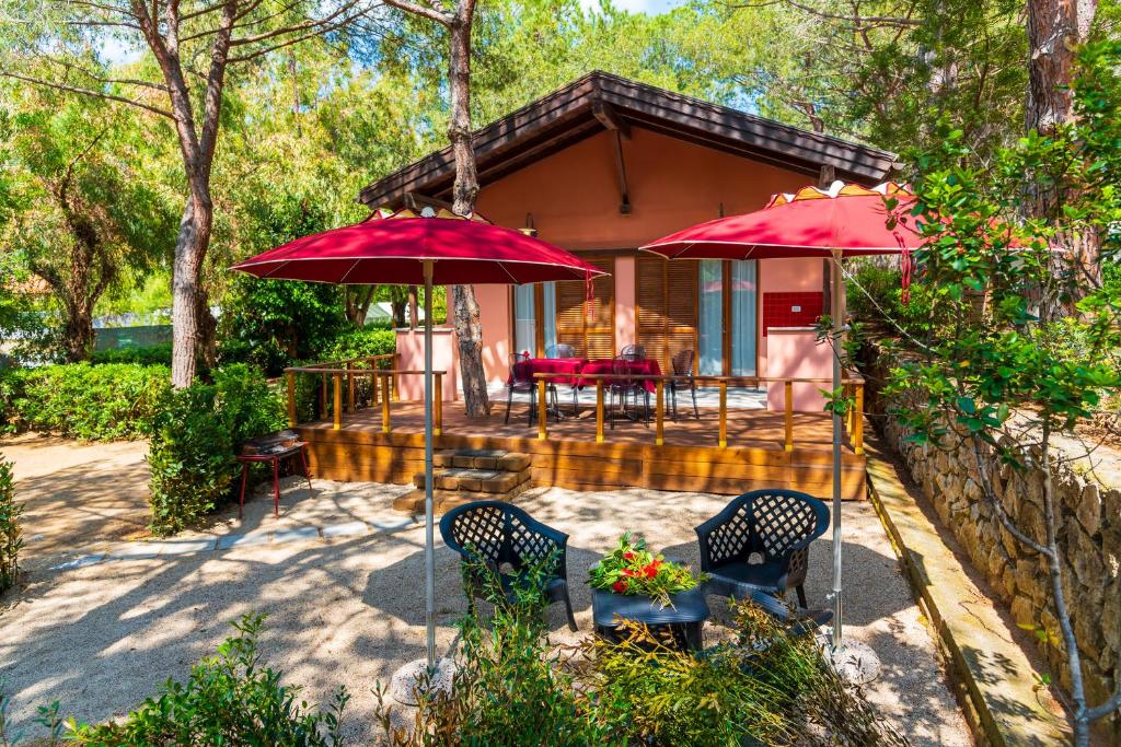 una casa con due ombrelloni rossi e un patio di Camping Lacona Pineta a Capoliveri