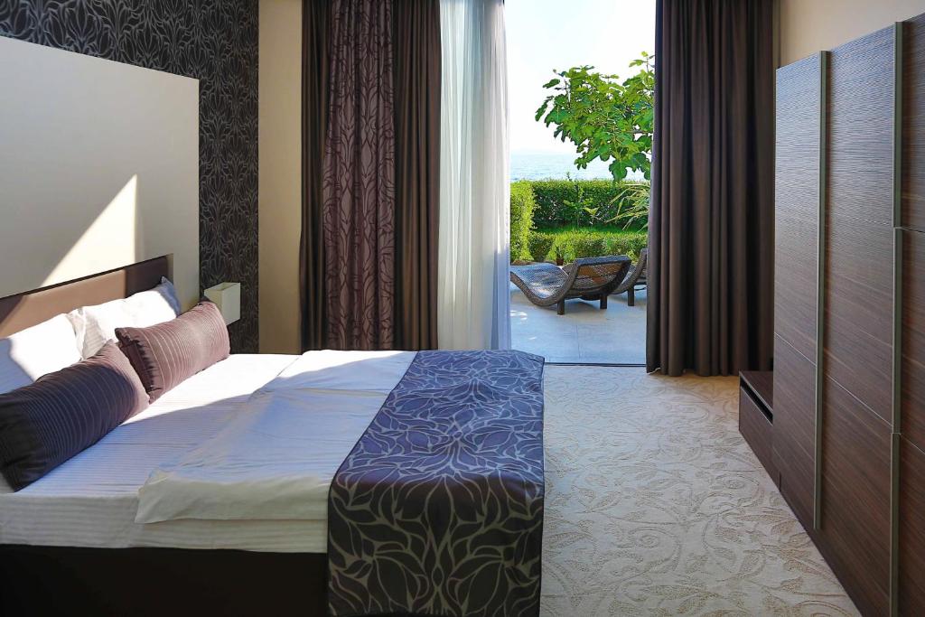 ein Hotelzimmer mit einem Bett und einer Glasschiebetür in der Unterkunft Hotel Beach Split in Podstrana