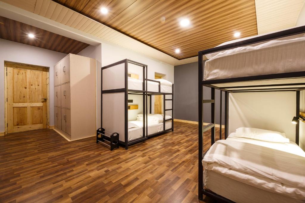 HITCHHIKERS HOSTEL LADAKH في ليه: غرفة بسريرين بطابقين وأرضية خشبية