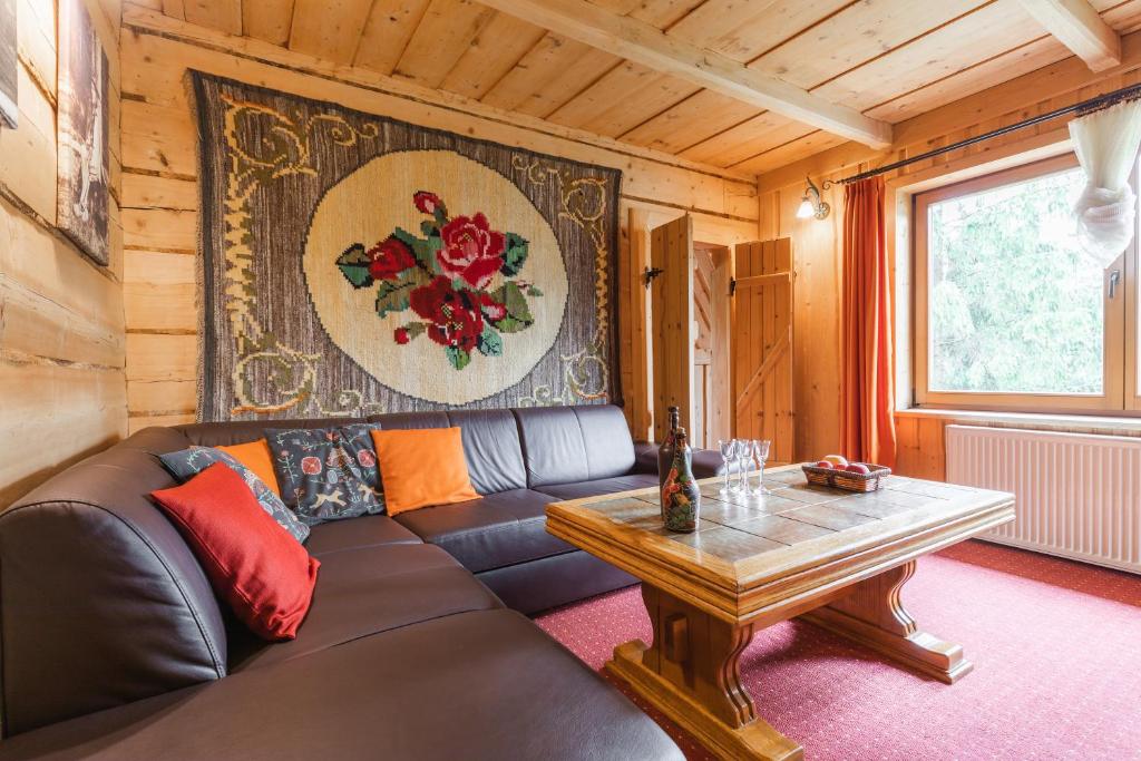 a living room with a leather couch and a table at Góralskie apartamenty, blisko centrum i wyciągu narciarskiego in Zakopane