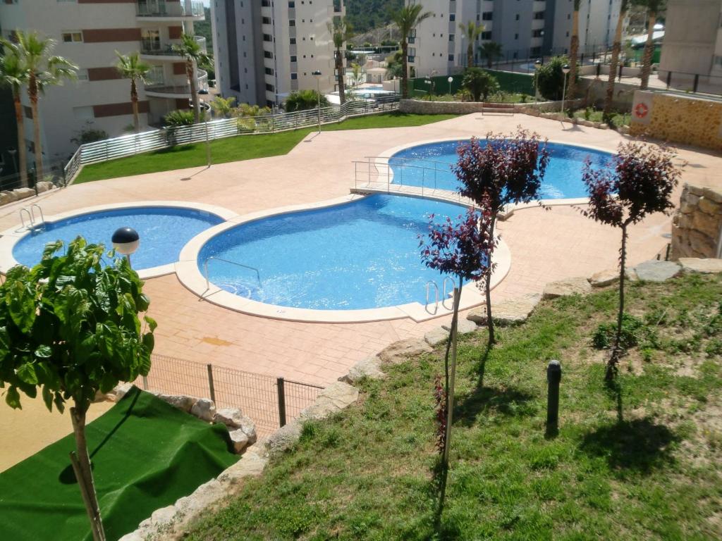 einen Pool inmitten eines Gartens mit Bäumen in der Unterkunft Apartment Torre Maestral by Interhome in Cala de Finestrat