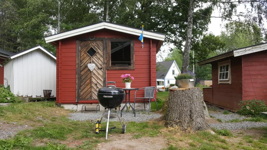 eine rote Hütte mit Grill im Hof in der Unterkunft Sollyckan in Knivsta