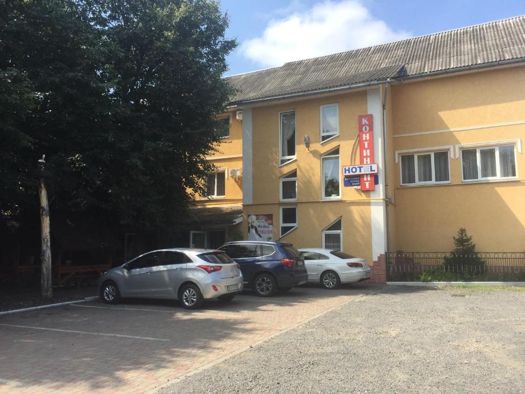 three cars parked in a parking lot in front of a hotel at Kontinent Hotel in Mukacheve