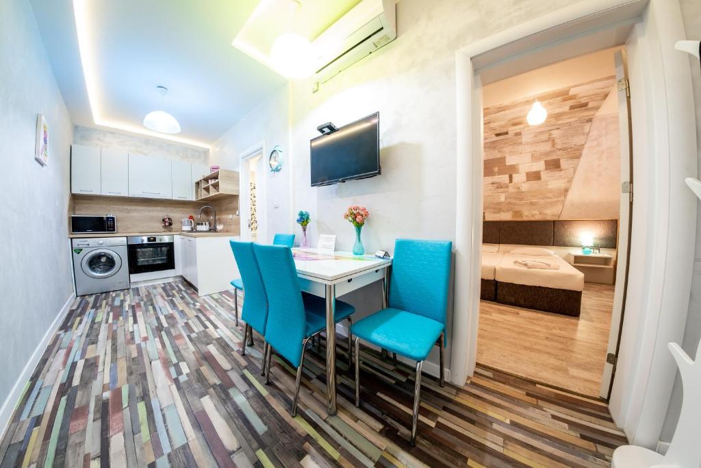 a kitchen and living room with a table and blue chairs at Sofia Colour Life Apartment -No Window Apartment in Sofia