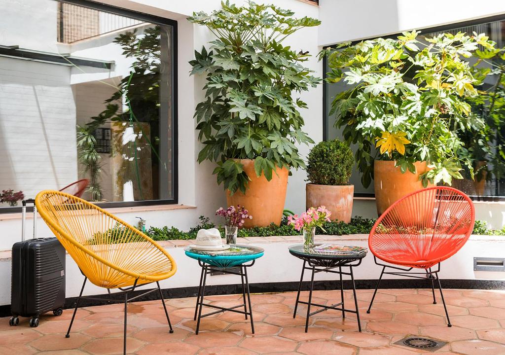 eine Terrasse mit 3 Stühlen und einem Tisch mit Blumen in der Unterkunft Feria Pool & Luxury in Sevilla