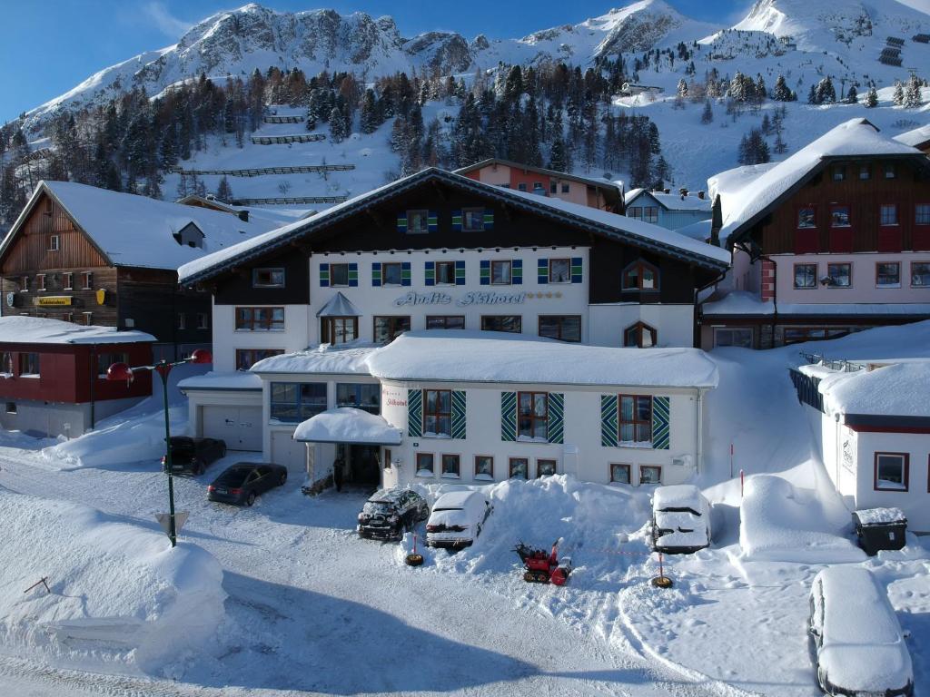 a building covered in snow in front of a mountain at Andi's Skihotel in Obertauern