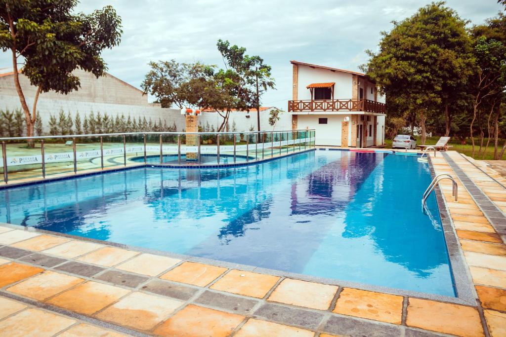 a swimming pool with blue water in front of a house at Hotel Ibiapaba in Tianguá