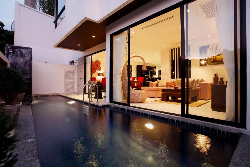 an infinity pool in a house with a living room at By The Lake Villas in Nai Harn Beach
