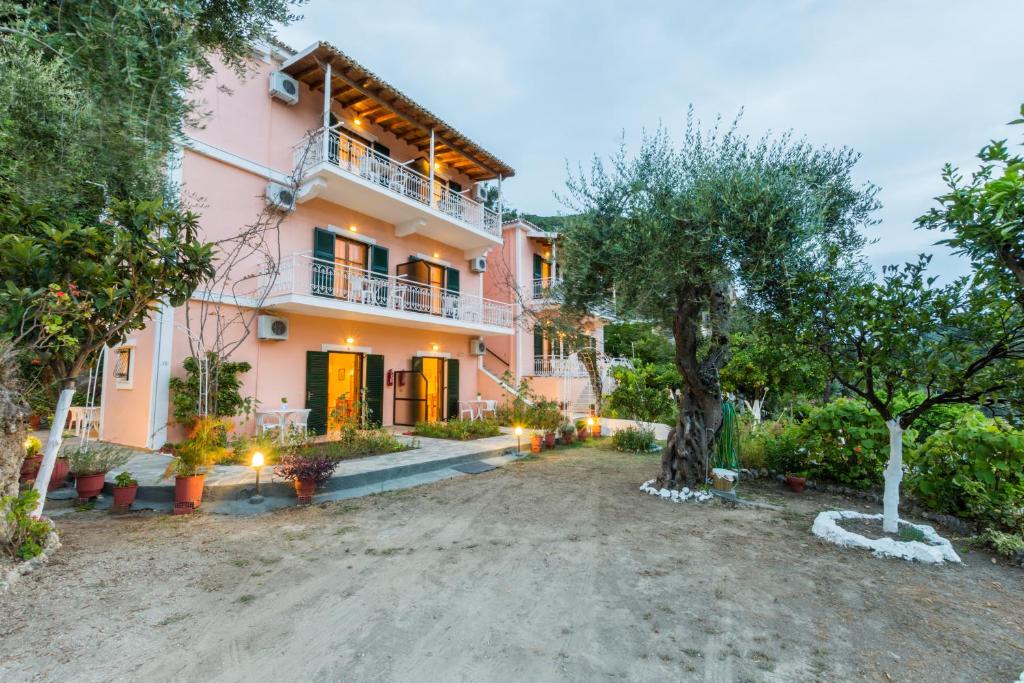 una vista exterior de una casa rosa con árboles en Villa Maria Makri, en Paleokastritsa