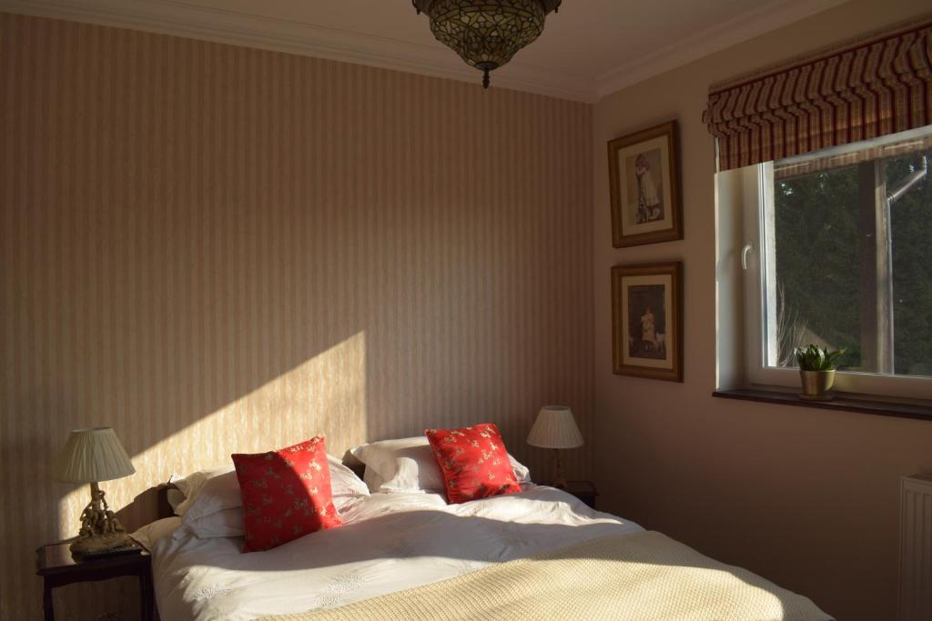 um quarto com uma cama com almofadas vermelhas e uma janela em Zakątek Warmiński em Płoskinie