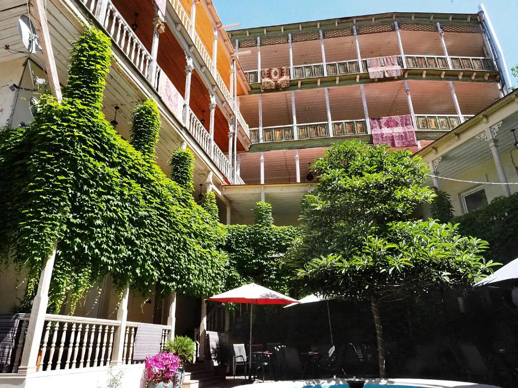 a building with an umbrella and trees in front of it at Hotel Nata in Tbilisi City