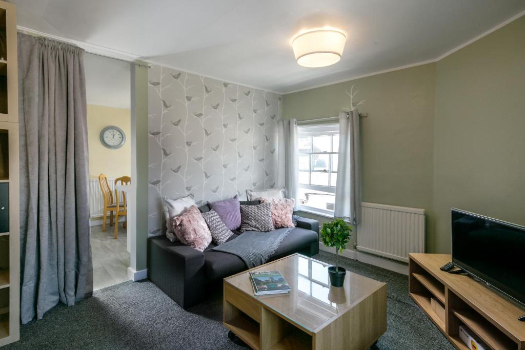 a living room with a couch and a tv at Lighthouse of Stowmarket in Stowmarket